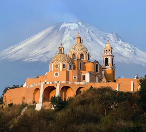 Puebla Cholula pyramid with volcano backdrop on Mexico City to Puebla tour.