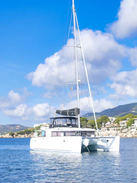 Catamaran sailing on clear waters near Mallorca coastline.