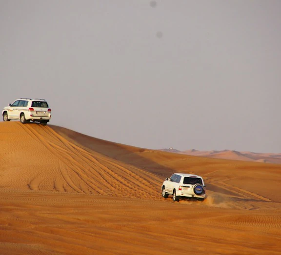 Dubai desert safari with off-road vehicle on sand dunes.