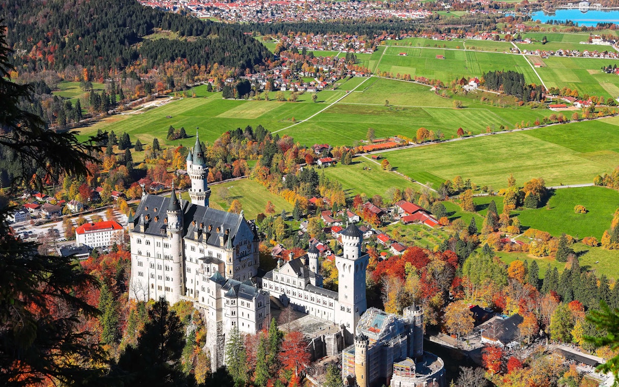 Aerial view of Neuschwanstein Castle surrounded by autumn foliage in Bavaria, Germany.