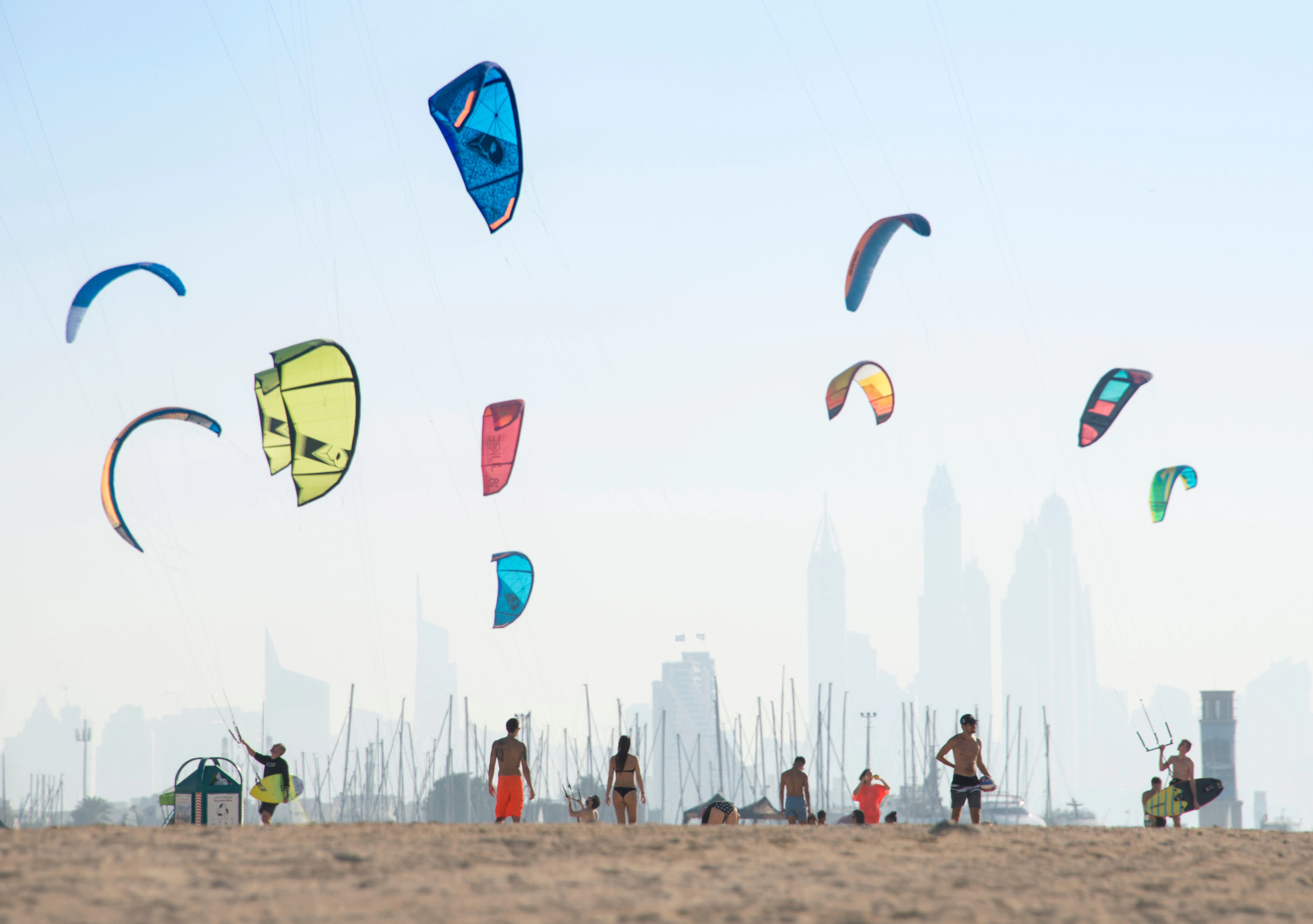 Kite surfers at Kite Beach with Dubai skyline in the background.