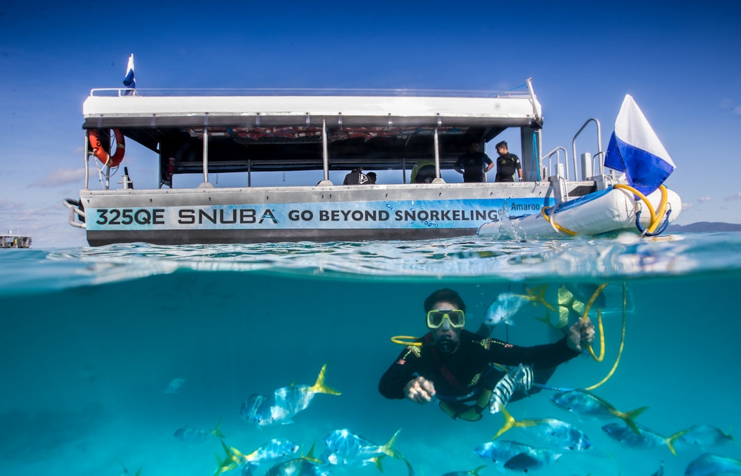 Tourists enjoying a Green Island cruise with a view of the lush coastline and clear blue waters.