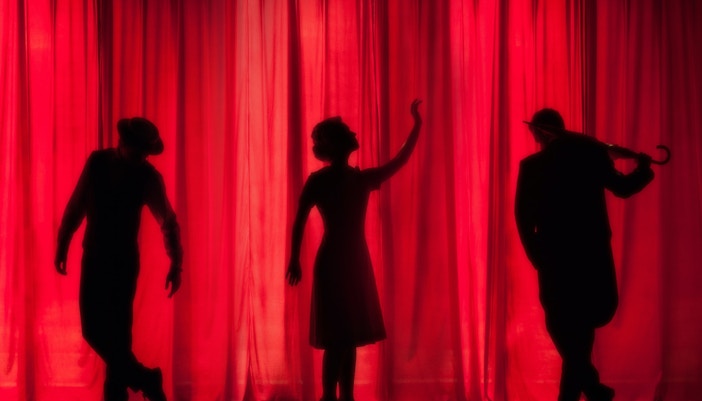 Silhouettes of performers in front of red stage curtains, illustrating Broadway etiquette.