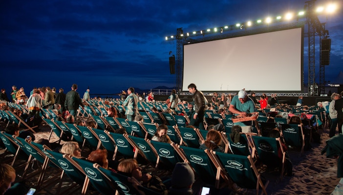 Outdoor cinema setup with large screen and seating in Dubai at sunset.