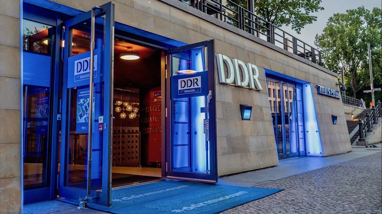 DDR Museum entrance in Berlin with open doors and illuminated signage.