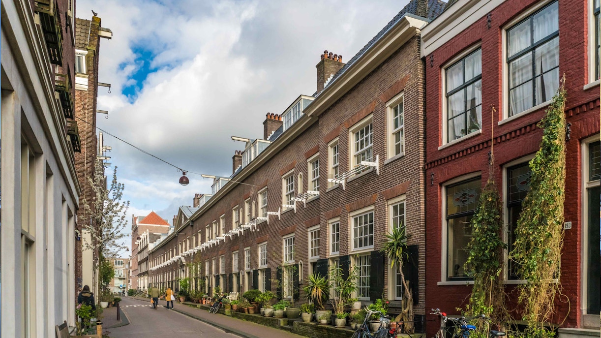 Jordaan district canal view in Amsterdam, featuring historic buildings and houseboats.