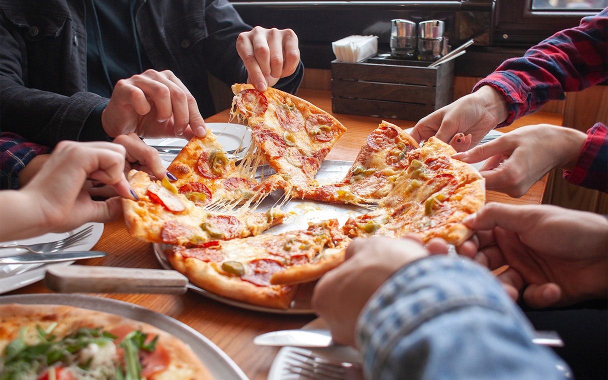 People sharing a pepperoni pizza at a restaurant in West End.