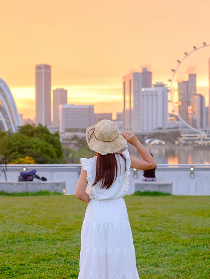 Tourist admiring Singapore skyline with Marina Bay Sands and Singapore Flyer at sunset.