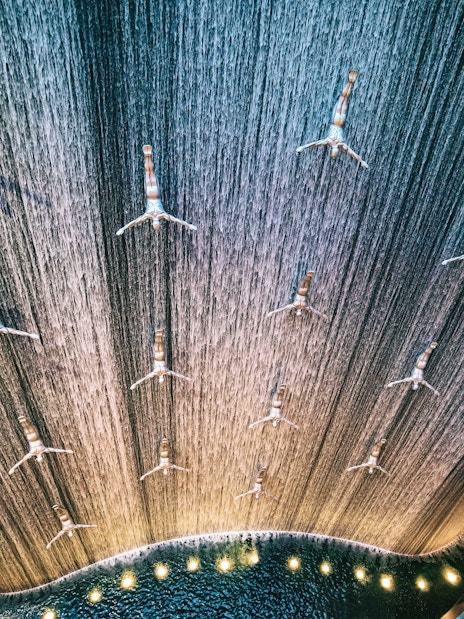 Waterfall installation with diving sculptures at Dubai Mall.