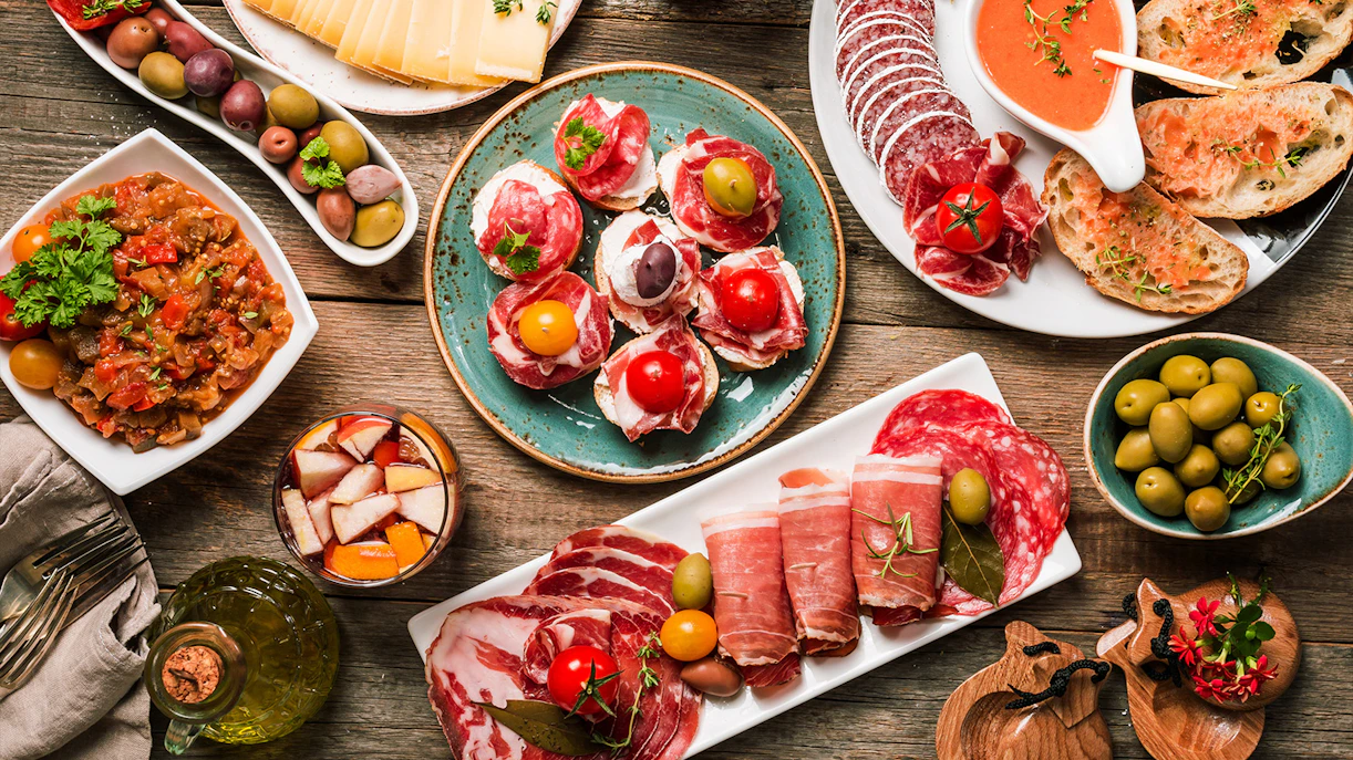 Assorted tapas and antipasti platter with olives, cured meats, and cheese in West End.