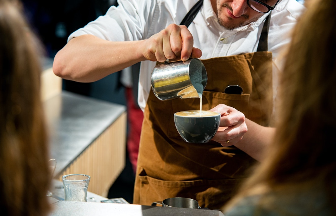 Barista pouring milk into coffee at Coffee Fest