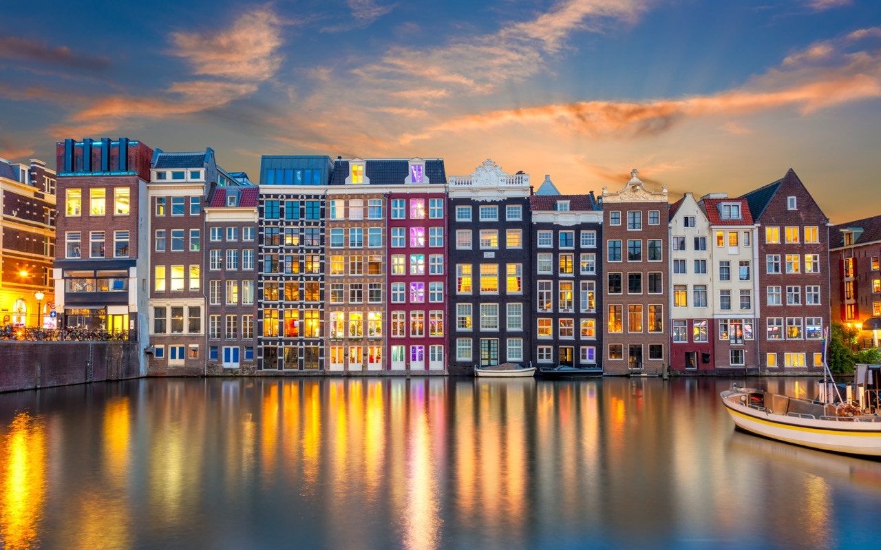 Damrak street view in Amsterdam with historic buildings and canal boats.