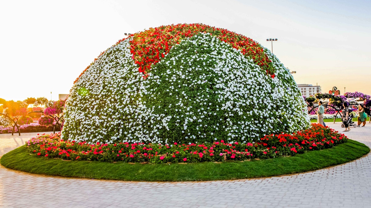 Dome-shaped floral display at Dubai Miracle Garden with red and white flowers.