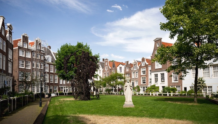 Amsterdam Begijnhof courtyard with historic buildings and lush greenery.