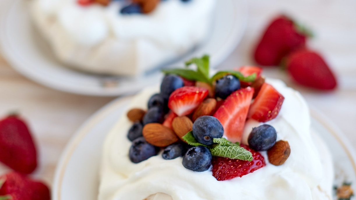 Pavlova topped with strawberries, blueberries, and almonds, served on a plate in Sydney.