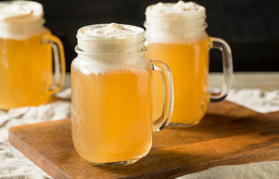 Butterbeer in glass mugs on a wooden board.