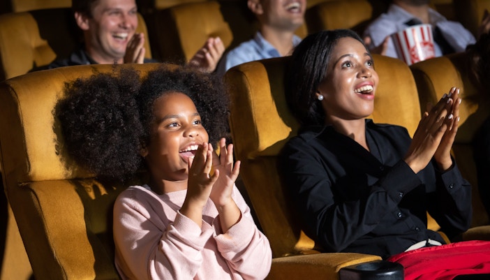 Family enjoying a theatre performance in a grand auditorium, London.