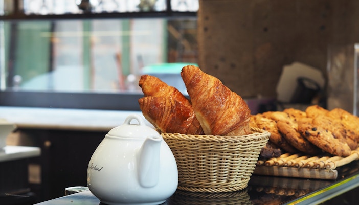 Freshly baked croissant with a jar of espresso on a New York café table.