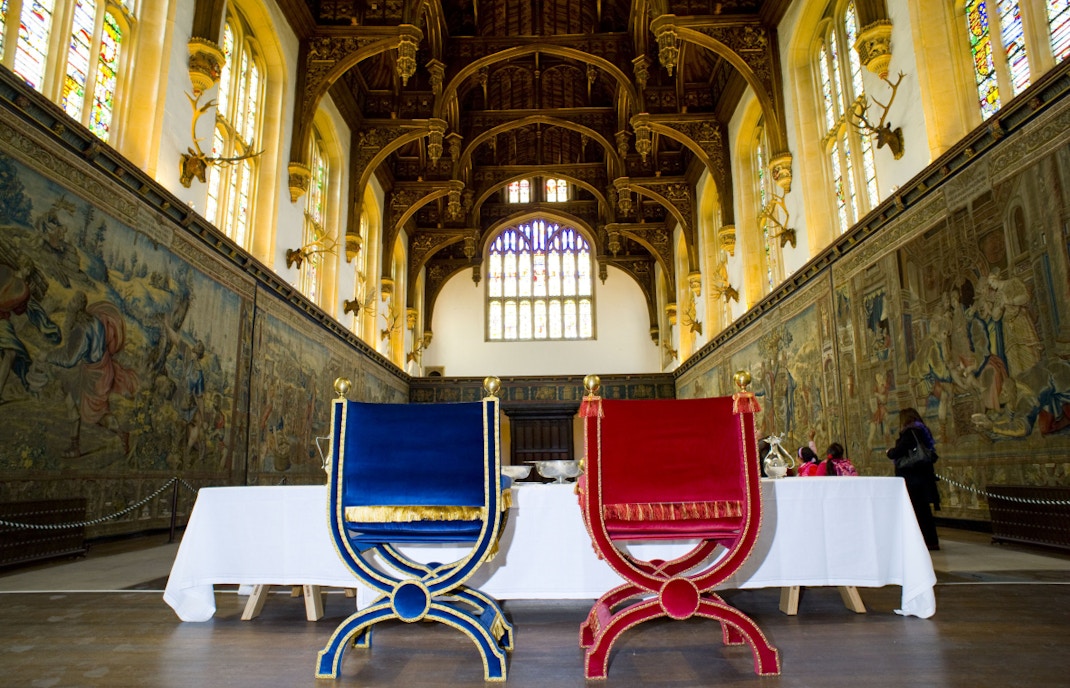 Great Hall at Hampton Court Palace with ornate chairs and tapestries.