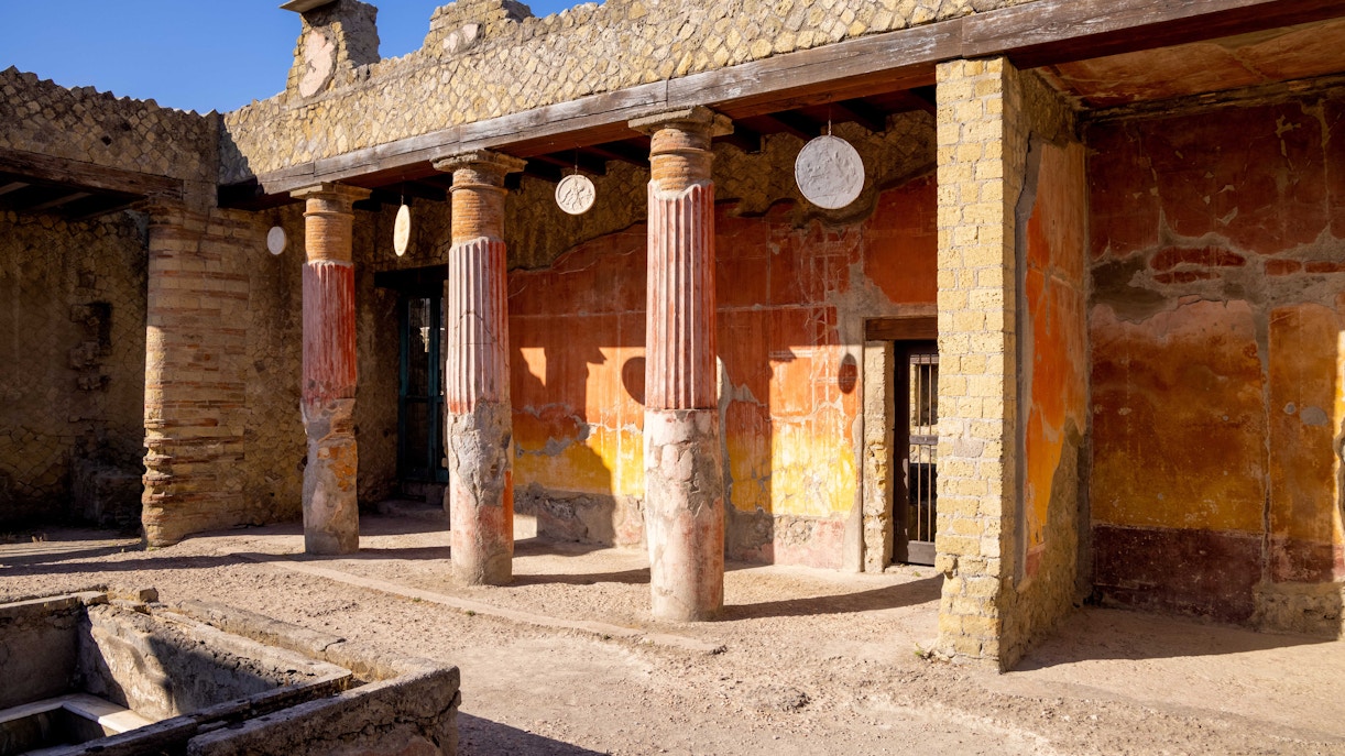 Ancient columns and walls at Herculaneum ruins, Italy, during a guided tour.