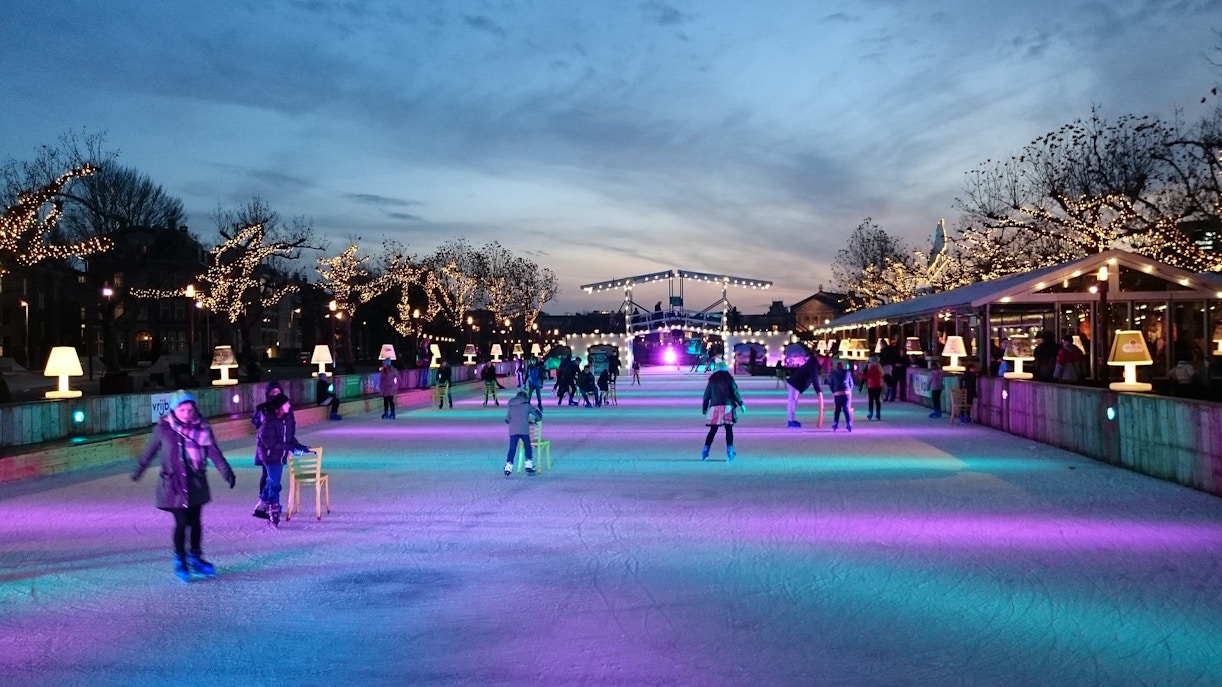 Ice skaters on a festive rink with illuminated trees in London during Christmas.