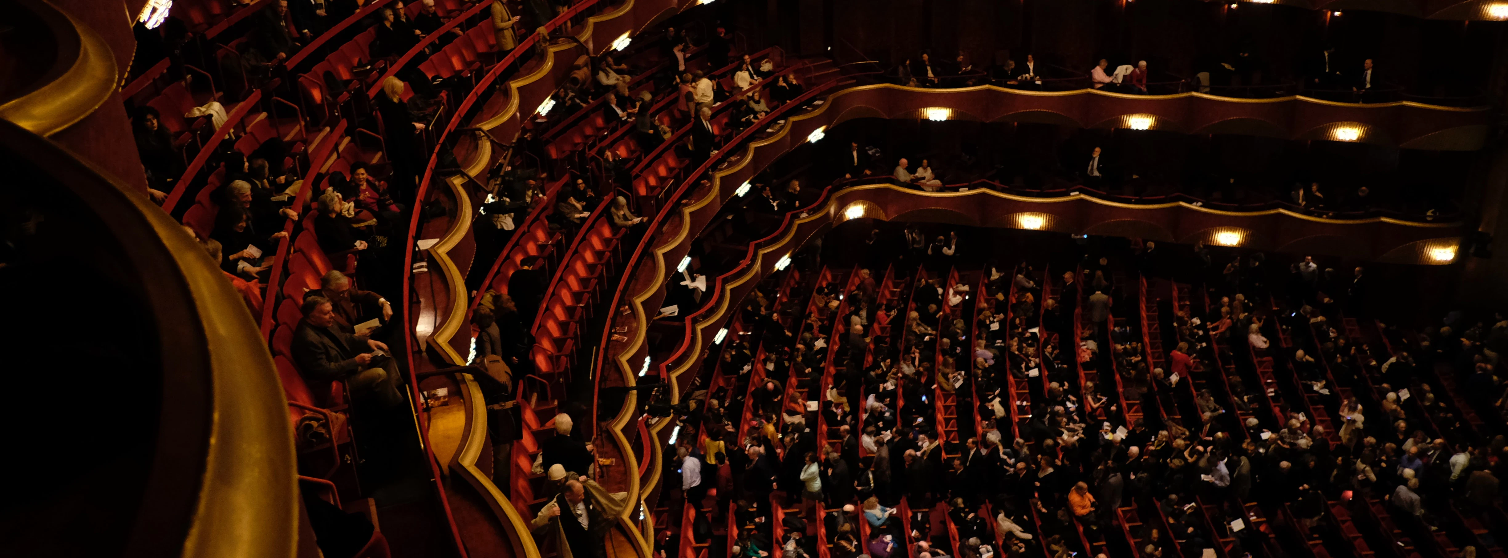 Off-Broadway theater seating sections filled with audience members.