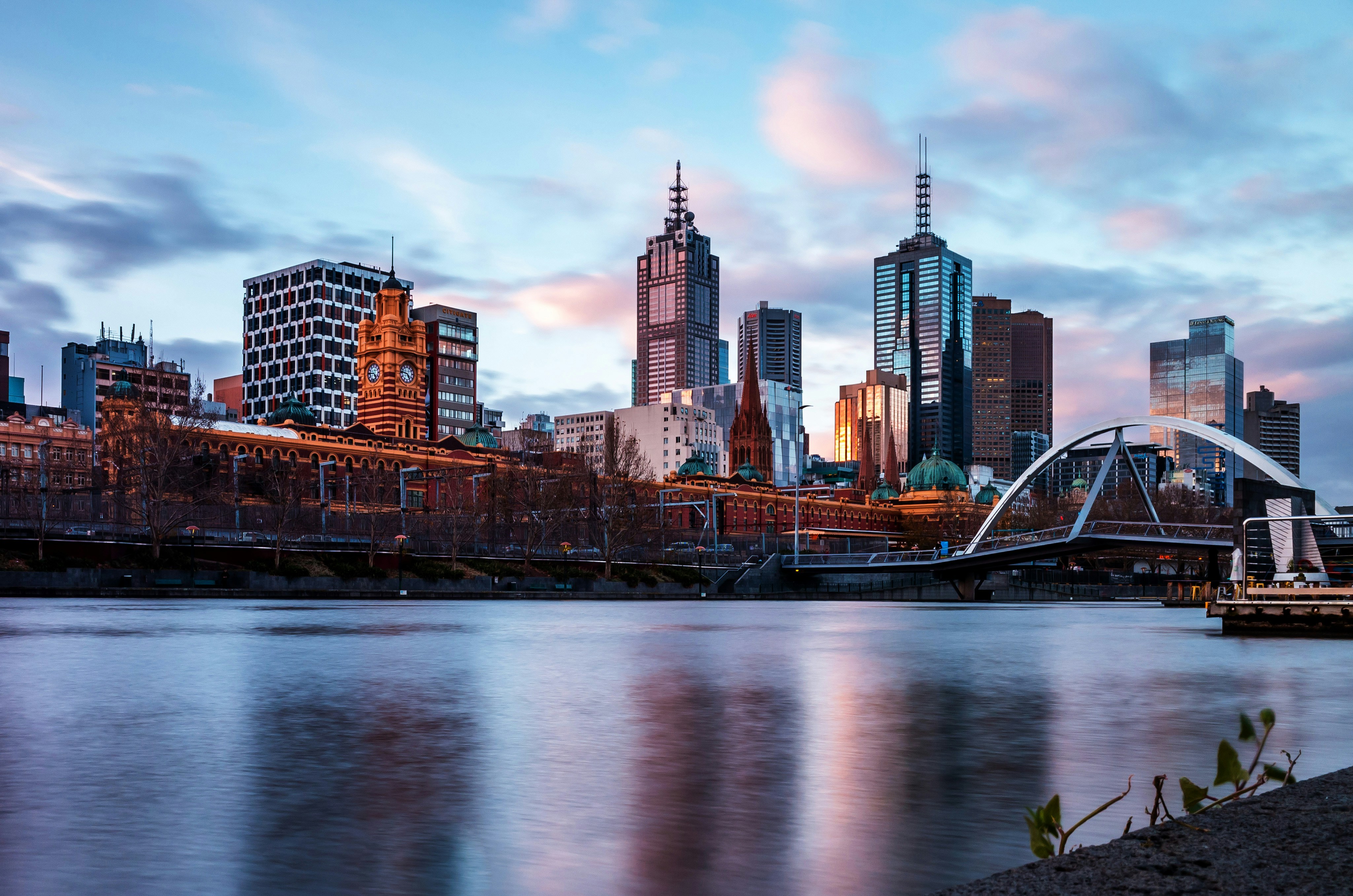 Melbourne skyline with Yarra River and iconic buildings at sunset.