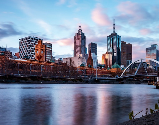 Melbourne skyline with Yarra River and iconic buildings at sunset.