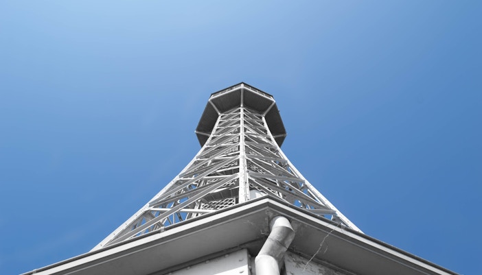 Petrin Tower in Prague against a clear blue sky, viewed from below.