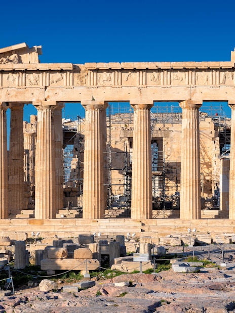 Parthenon at Acropolis, Athens, Greece, viewed from the front with ancient ruins in foreground.