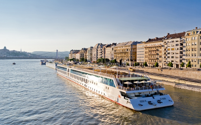 Cruise ship on Danube River with Budapest cityscape, part of 24 Hour Budapest Big Bus HOHO tour.