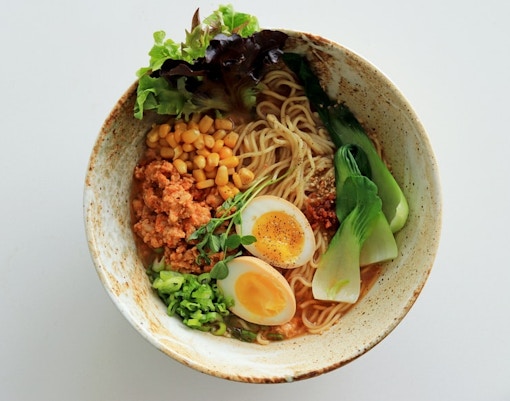A bowl of ramen is shown, featuring noodles in a savory broth, topped with a variety of ingredient