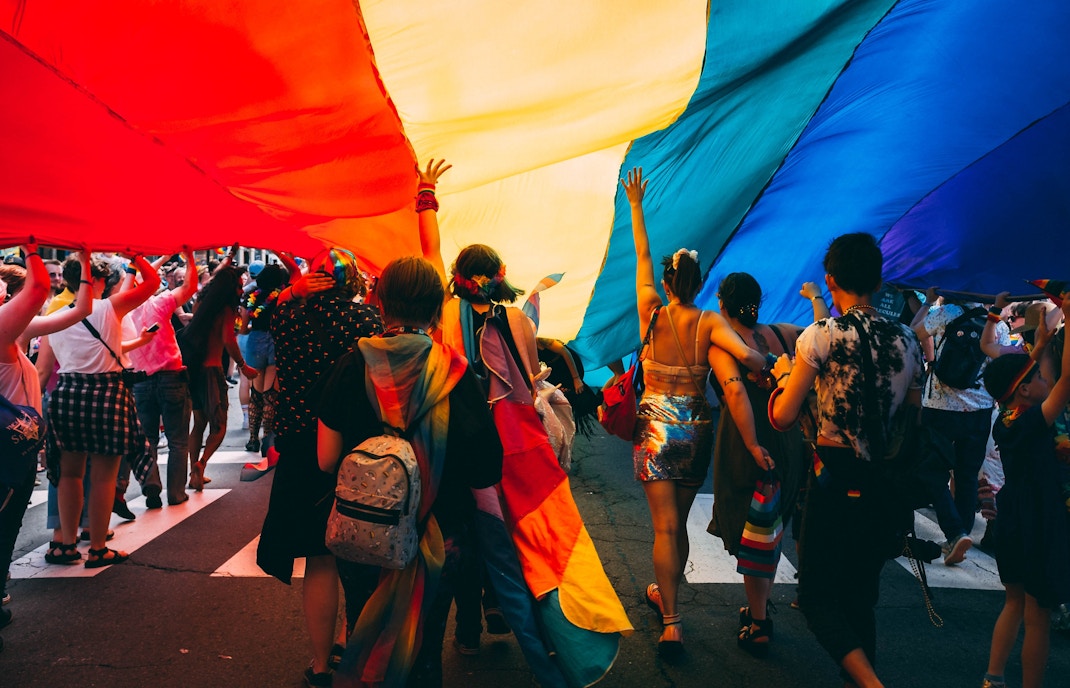 People celebrating Prague Pride parade with rainbow flags in front of historic buildings.