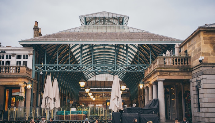 Covent Garden market entrance with people sitting outside in London.