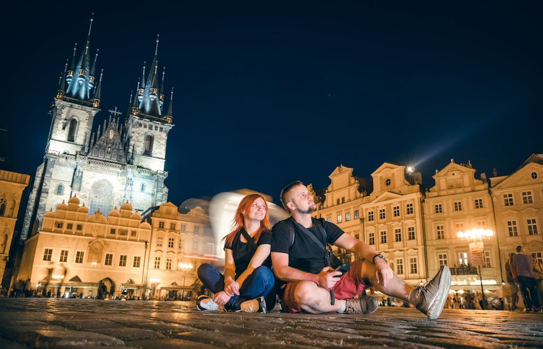 couple sit in the main square on the street of the old city of Prague, night time