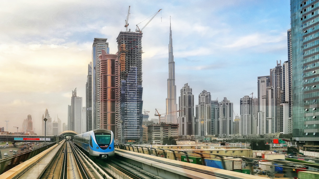 Dubai Metro train traveling with city skyscrapers in the background.