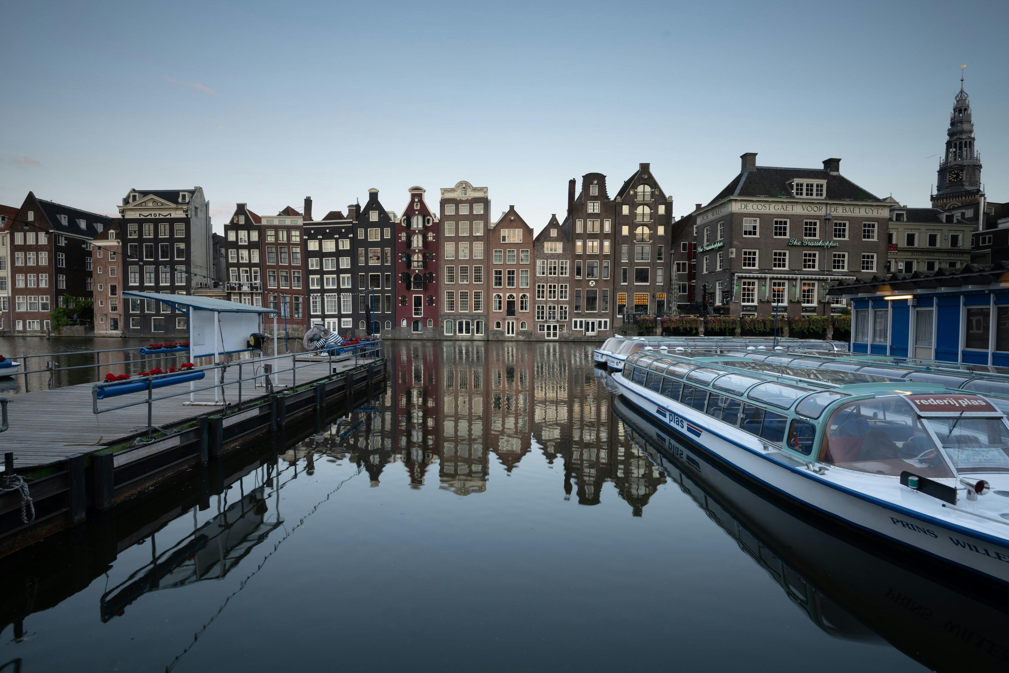 Canal houses and tour boats along Damrak in Amsterdam.