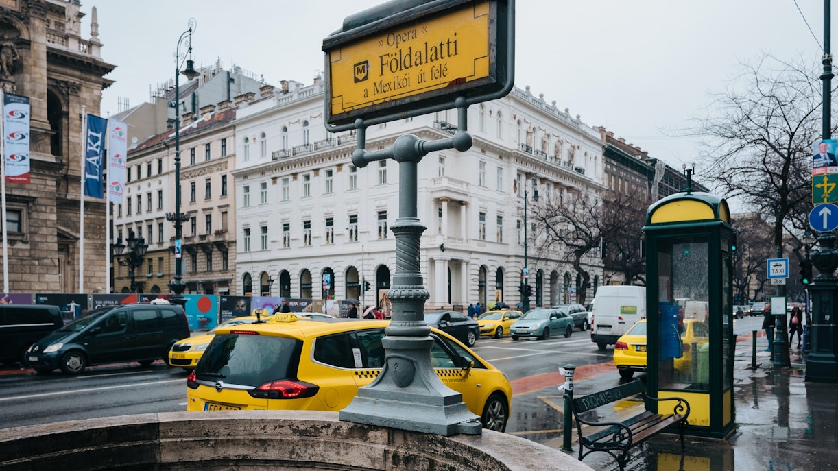 Street view near Hungarian State Opera, Budapest, with taxis and metro sign.
