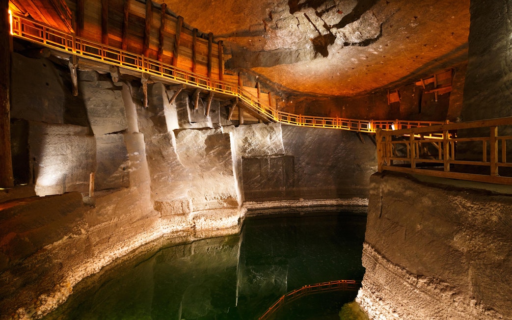 Wieliczka Salt Mine underground chamber with wooden walkway and reflective water surface.