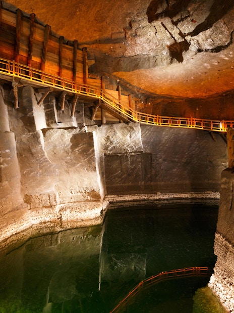 Wieliczka Salt Mine underground chamber with wooden walkway and reflective water surface.
