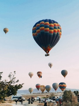 Hot air balloons over Cappadocia landscape during a day tour.