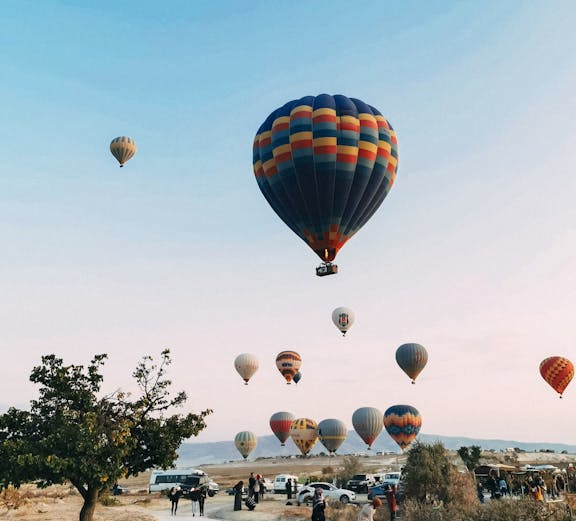 Hot air balloons over Cappadocia landscape during a day tour.