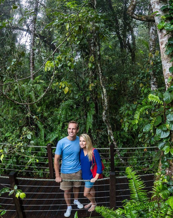 Visitors on a boardwalk in Kuranda rainforest, Cairns, surrounded by lush greenery.