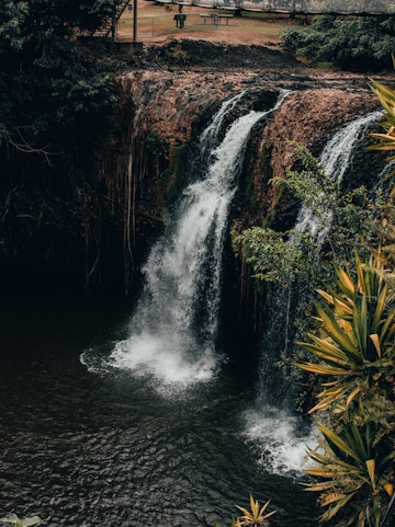 Waterfall at Paronella Park, Cairns, surrounded by lush greenery and viewing platform.