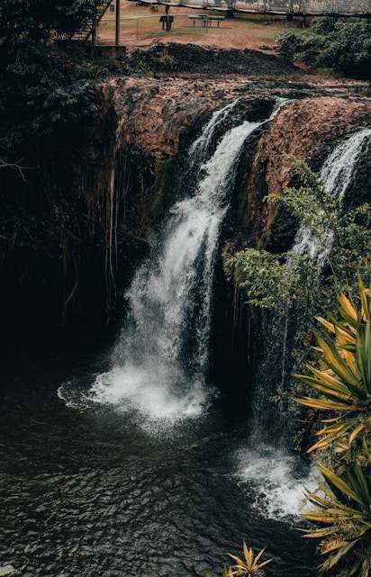 Waterfall at Paronella Park, Cairns, surrounded by lush greenery and viewing platform.