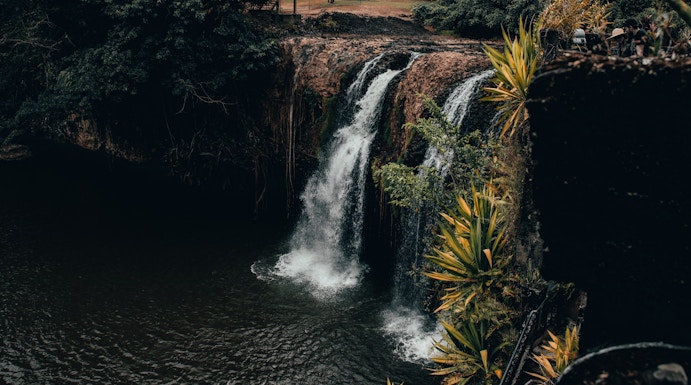 Waterfall at Paronella Park, Cairns, surrounded by lush greenery and viewing platform.