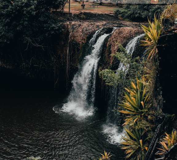 Waterfall at Paronella Park, Cairns, surrounded by lush greenery and viewing platform.
