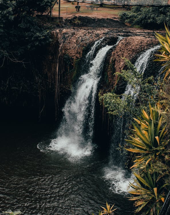Waterfall at Paronella Park, Cairns, surrounded by lush greenery and viewing platform.