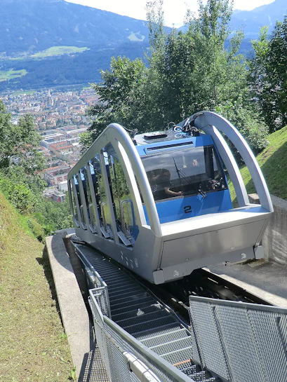 Funicular ascending a mountain in Innsbruck with city view in the background.