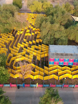 Dubai Wonder Maze aerial view with yellow walls and surrounding greenery.